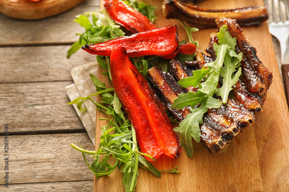 Delicious grilled ribs with arugula and pepper on wooden board Delicious grilled ribs with arugula and pepper on wooden board