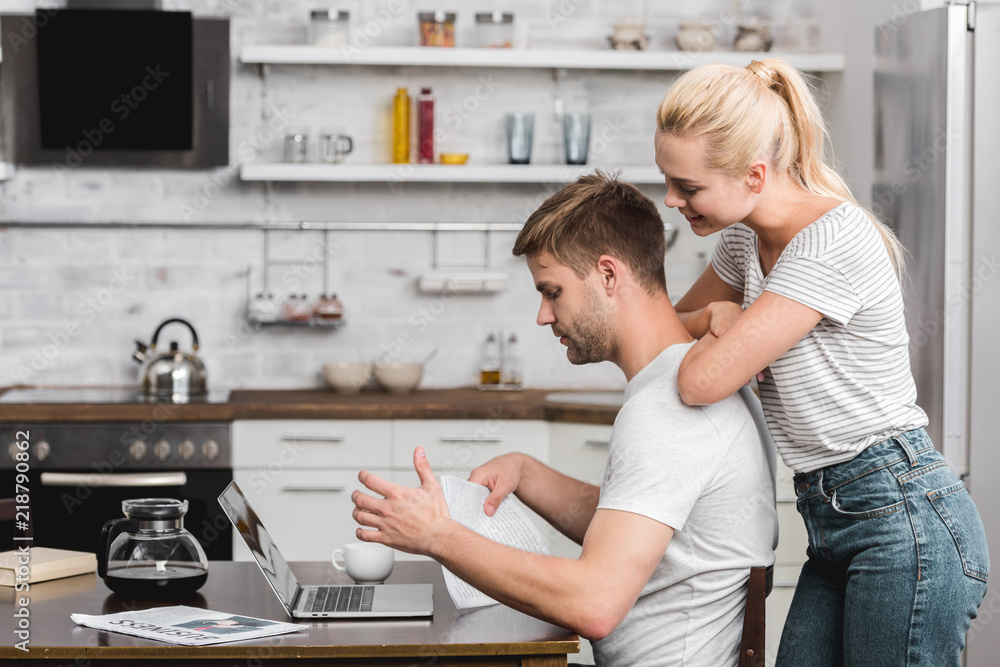 side view of young couple using laptop together at home side view of young couple using laptop together at home
