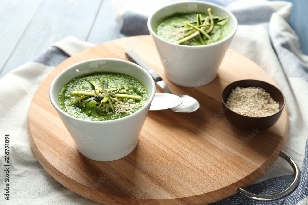 Tasty zucchini soup in bowls on wooden board Tasty zucchini soup in bowls on wooden board