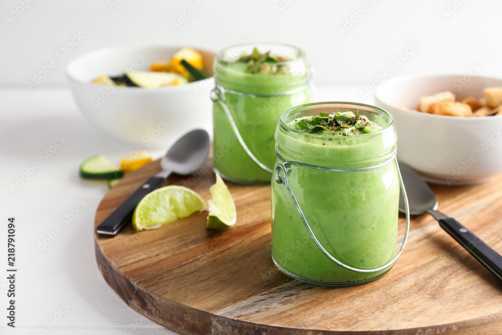Tasty zucchini soup in jars on wooden board Tasty zucchini soup in jars on wooden board