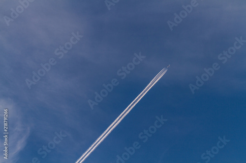 the airplane is flying on a blue sky leaving a trail