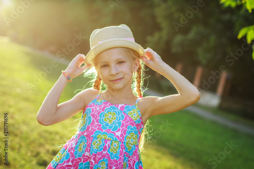 Pretty teen girl posing in hat among summer and sunset