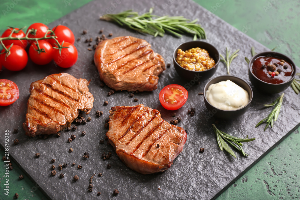 Tasty grilled steaks with different sauces on slate plate Tasty grilled steaks with different sauces on slate plate