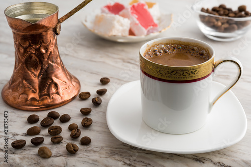 Vintage cup of turkish coffee and traditional bronze coffee pot served on marble with turkish delights