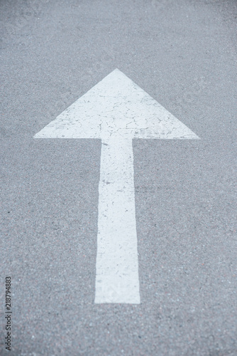 large white arrow symbol drawn on asphalt road