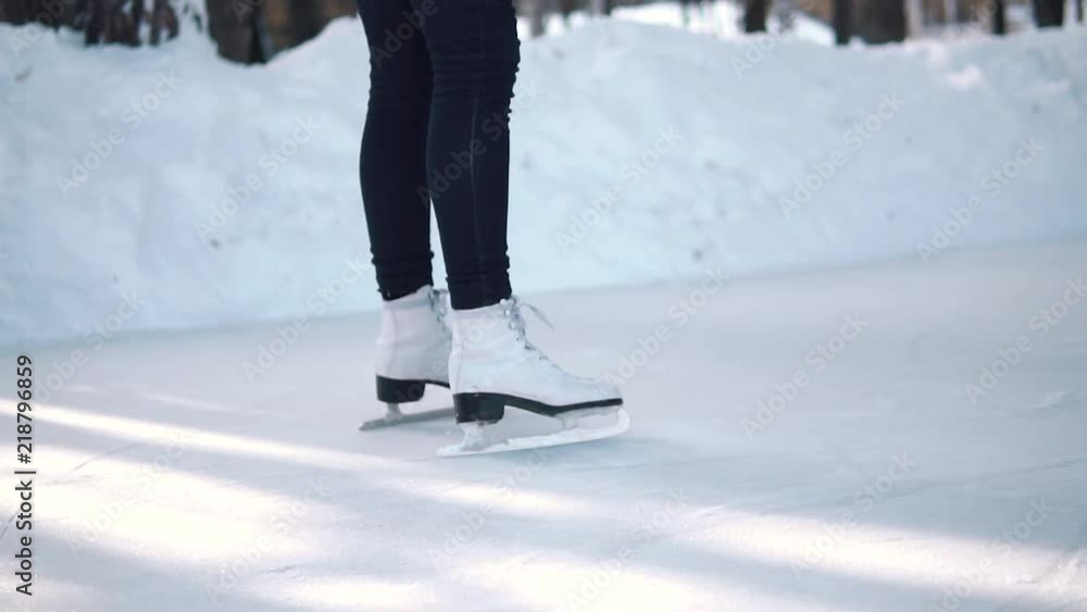women's skates close-up. girl skates on a skating rink in a winter forest. slow motion women's skates close-up. girl skates on a skating rink in a winter forest. slow motion