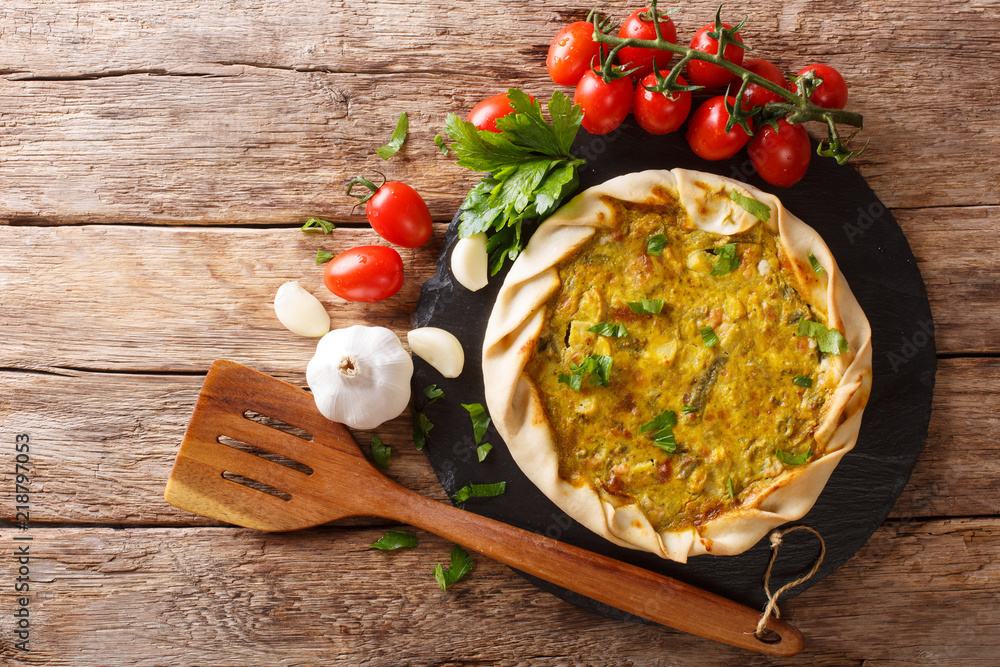 Spicy potato savory tart with vegetables and herbs close up on the table. horizontal top view Spicy potato savory tart with vegetables and herbs close up on the table. horizontal top view