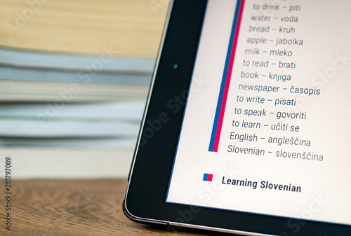 Learning Slovenian using a tablet with books in the background.