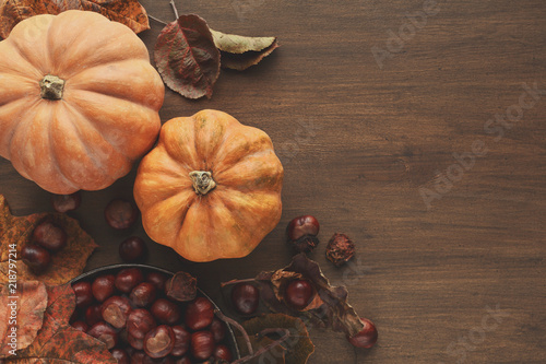 Beautiful pumpkins with leaves and chestnuts on wooden table photo