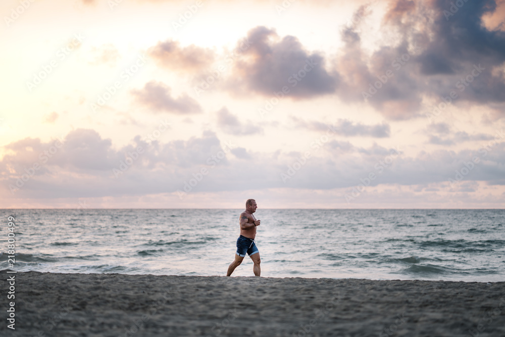 Strong old man makes exercise on the beach. Strong old man makes exercise on the beach.