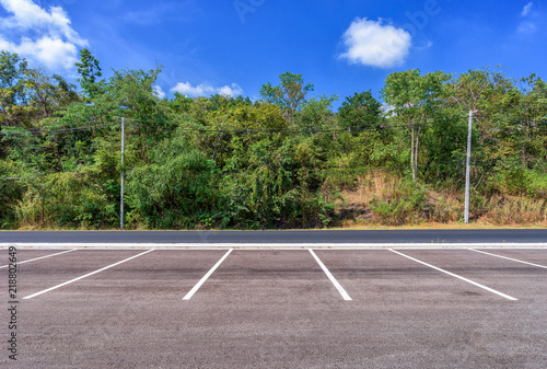 Empty parking lot with forest and beautiful blue sky.
