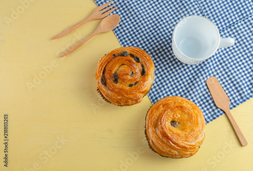 Obraz na płótnie Raisin danish pastry on the yellow wood and blue gingham check cloth. Colourful tasty sweet bakery.. w salonie