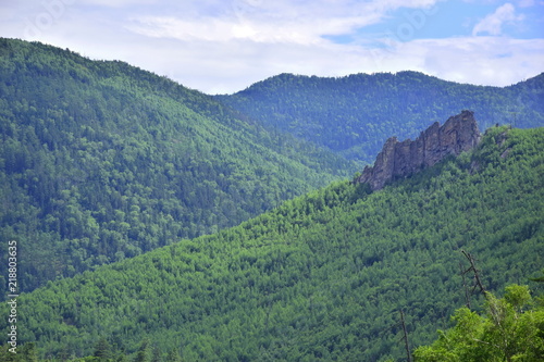 Blue-green mountains of the Sikhote-Alin. The green sea of taiga, hills and passes, rocks and blue sky are the splendor of the mountains. Russian far East. The mountains of Sikhote-Alin.