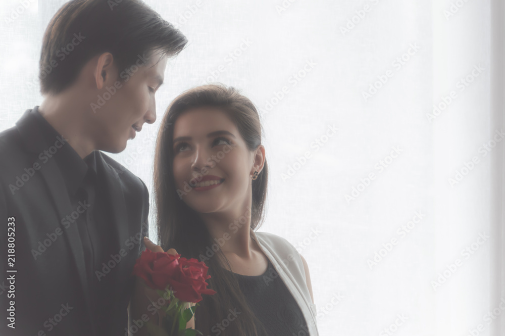 Couple are romantic in love, and holding red rose flower in her hand, withe blurred white background Couple are romantic in love, and holding red rose flower in her hand, withe blurred white background