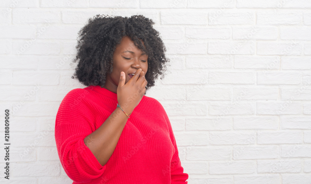 Young african american plus size woman over white brick wall bored yawning tired covering mouth with hand. Restless and sleepiness. Young african american plus size woman over white brick wall bored yawning tired covering mouth with hand. Restless and sleepiness.