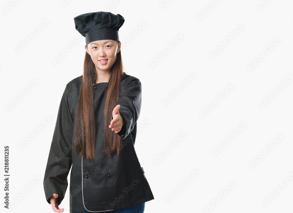 Young Chinese woman over isolated background wearing chef uniform smiling friendly offering handshake as greeting and welcoming. Successful business. Young Chinese woman over isolated background wearing chef uniform smiling friendly offering handshake as greeting and welcoming. Successful business.