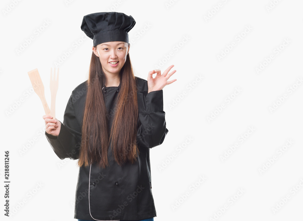 Young Chinese woman over isolated background wearing chef uniform doing ok sign with fingers, excellent symbol Young Chinese woman over isolated background wearing chef uniform doing ok sign with fingers, excellent symbol