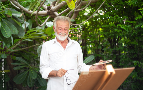 Elderly man painting something on a canvas in ther park happliy.Painting Concept,Lifestyle concept,Creative concept. photo