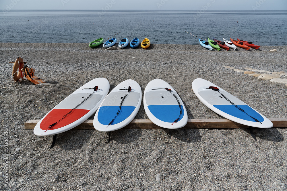 Surfboards on the background of kayaks on the coast.