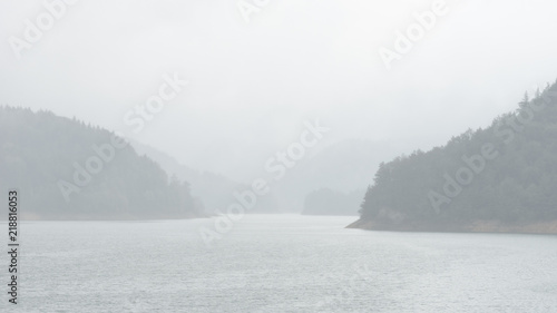 Bright hazy landscape view of Zaovine lake in rainy foggy weather in Tara national park, Serbia photo