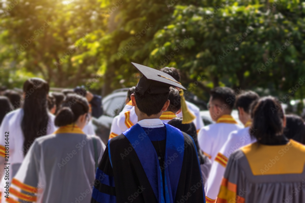 Obraz premium Soft focus of the crowded graduates celebrating commencement ceremony with joyful and fun. University graduation ceremony. Soft focus portrait of a graduate wearing black academic gown and cap.