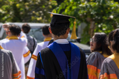 Soft focus of the crowded graduates celebrating commencement ceremony with joyful and fun. University graduation ceremony. Soft focus portrait of a graduate wearing black academic gown and cap.