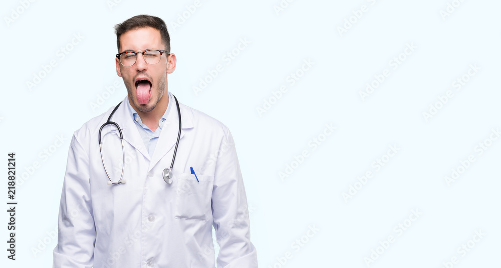 Handsome young doctor man sticking tongue out happy with funny expression. Emotion concept. Handsome young doctor man sticking tongue out happy with funny expression. Emotion concept.