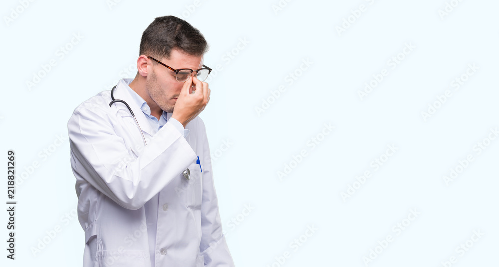 Handsome young doctor man tired rubbing nose and eyes feeling fatigue and headache. Stress and frustration concept. Handsome young doctor man tired rubbing nose and eyes feeling fatigue and headache. Stress and frustration concept.