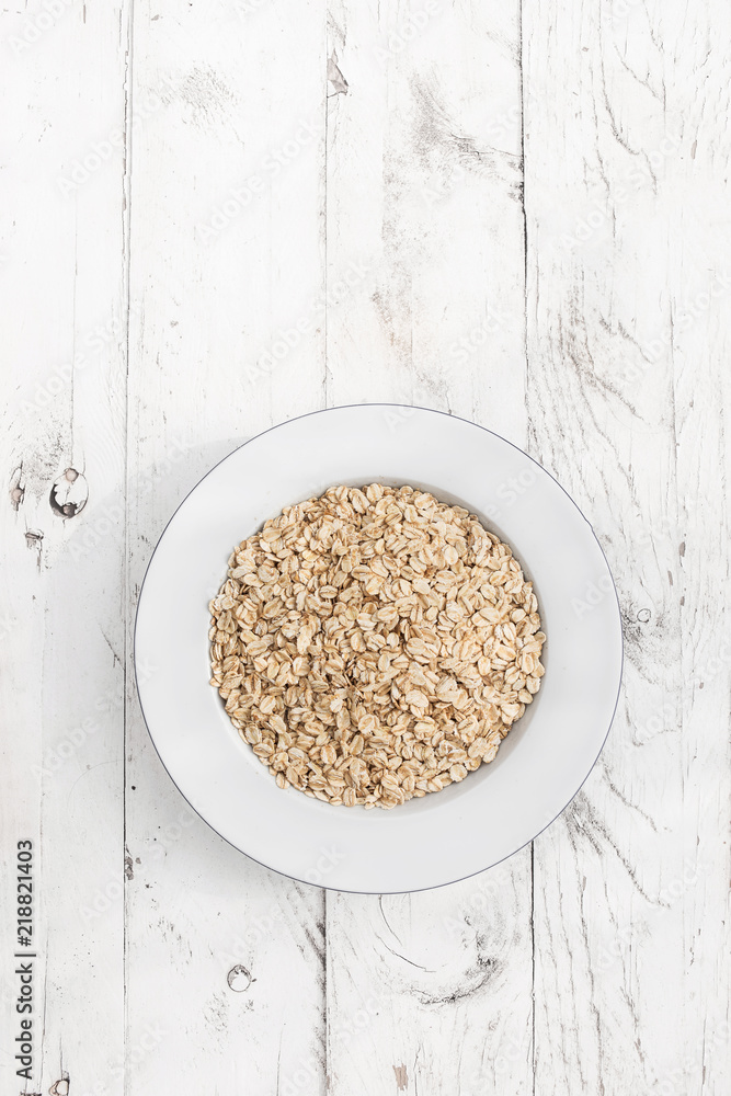 Oatmeal. Rolled oats flakes on white wooden background Oatmeal. Rolled oats flakes on white wooden background
