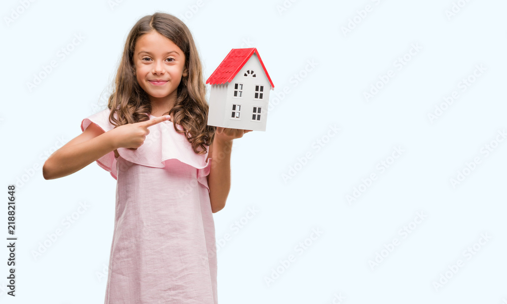 Brunette hispanic girl holding little house very happy pointing with hand and finger Brunette hispanic girl holding little house very happy pointing with hand and finger