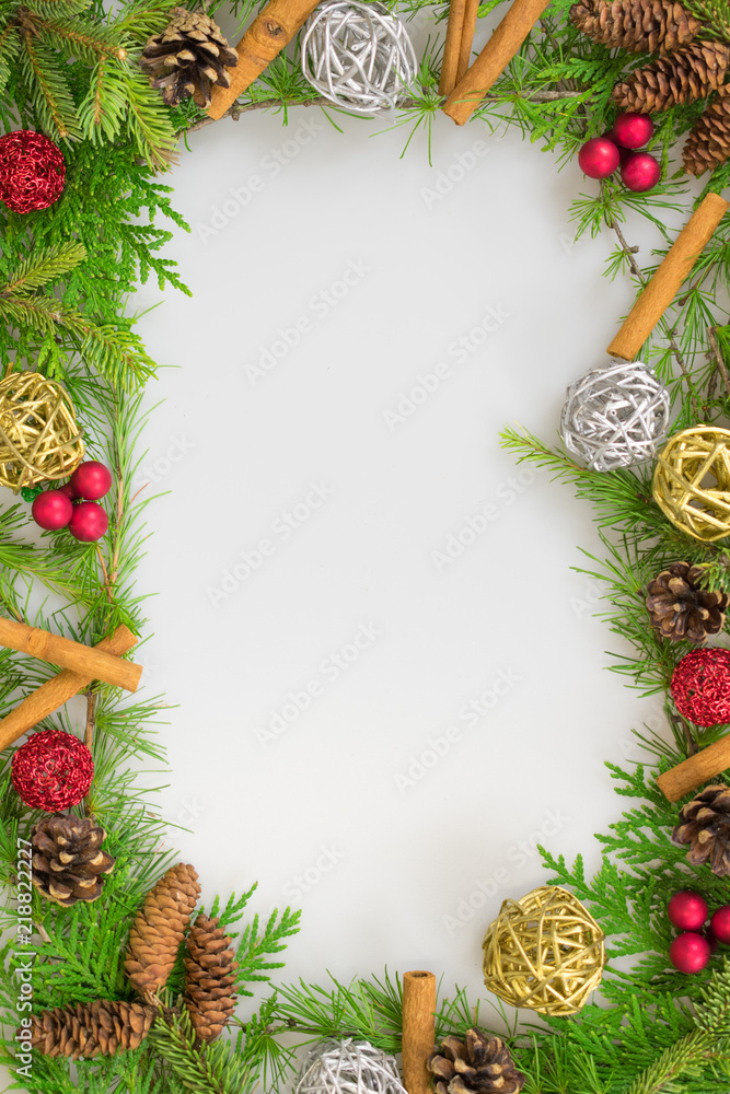 Border of evergreen branches with cinnamon sticks, twine and twig balls, berry clusters,  silver and gold twig balls, red ornaments, and pine cones