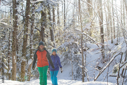 Pair of female friends snowshoeing in forest.