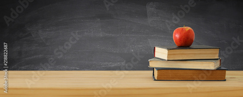 back to school banner. stack of books over wooden desk in front of blackboard. photo