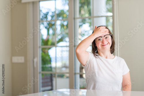 Down syndrome woman at home stressed with hand on head, shocked with shame and surprise face, angry and frustrated. Fear and upset for mistake. © Krakenimages.com