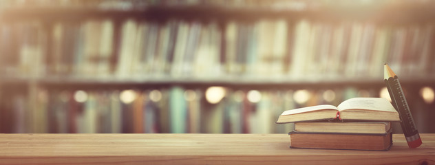 back to school concept. stack of books over wooden desk in front of library.