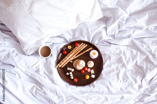 Tasty breakast on wooden tray in hotel room closeup. Top view. photo