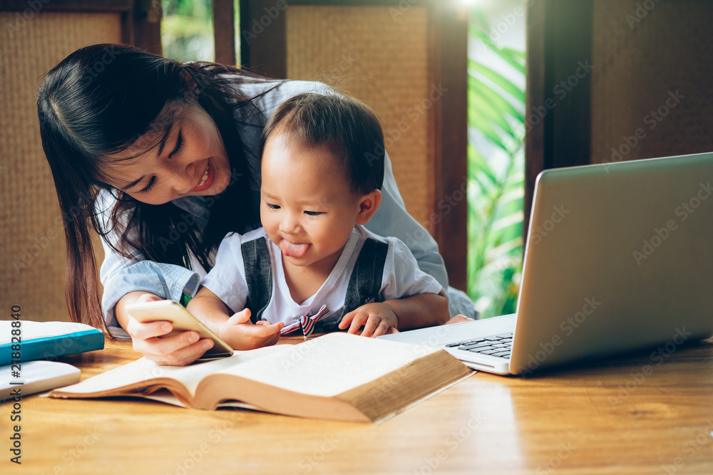 Business woman teaching her child about investment with multimedia and book, home school education. Business woman teaching her child about investment with multimedia and book, home school education.