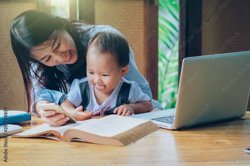 Business woman teaching her child about investment with multimedia and book, home school education. Business woman teaching her child about investment with multimedia and book, home school education.