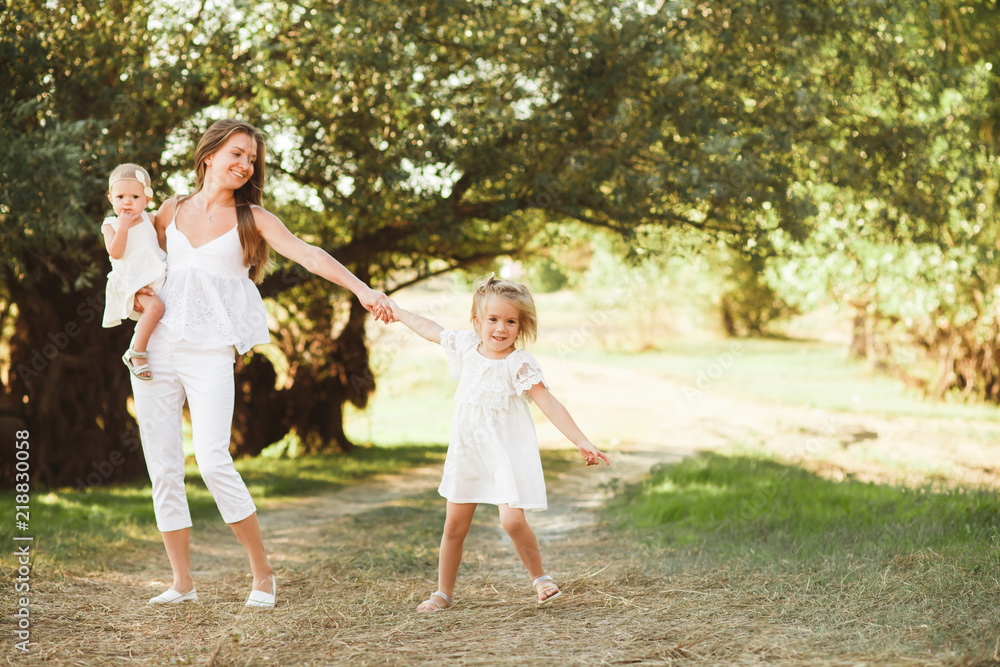Mom with two little daughters are walking among the beautiful green forest. Mom with two little daughters are walking among the beautiful green forest.