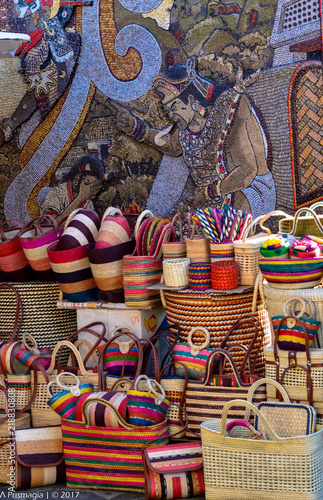 TEPOZTLAN, MORELOS/MEXICO – FEB 2017: Handmade purses on the streets in the magic town of Tepoztlan. In the background a mural made from seeds at the church gate, an indigenous tradition