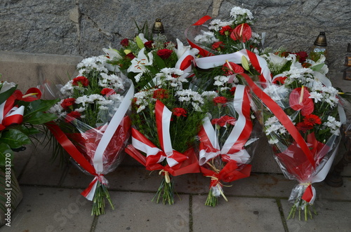 Biało-czerwone wiązanki złożone pod pomnikiem, polska symbolika