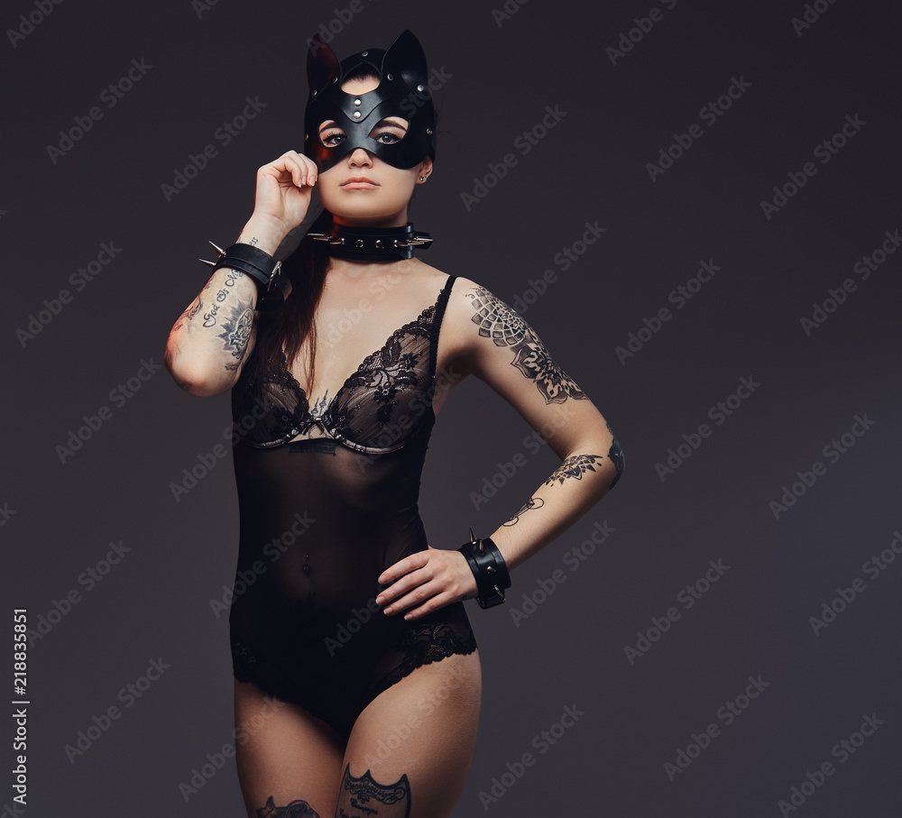 Sexy woman wearing black lingerie in BDSM cat leather mask and accessories posing on dark background. Sexy woman wearing black lingerie in BDSM cat leather mask and accessories posing on dark background.