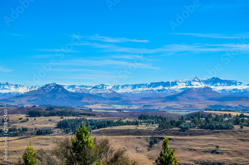 A picturesque blue landscape with snow clad drakensberg mountains and cotton type clouds in a small countryside called Underberg near sani pass and midlands in South Africa photo