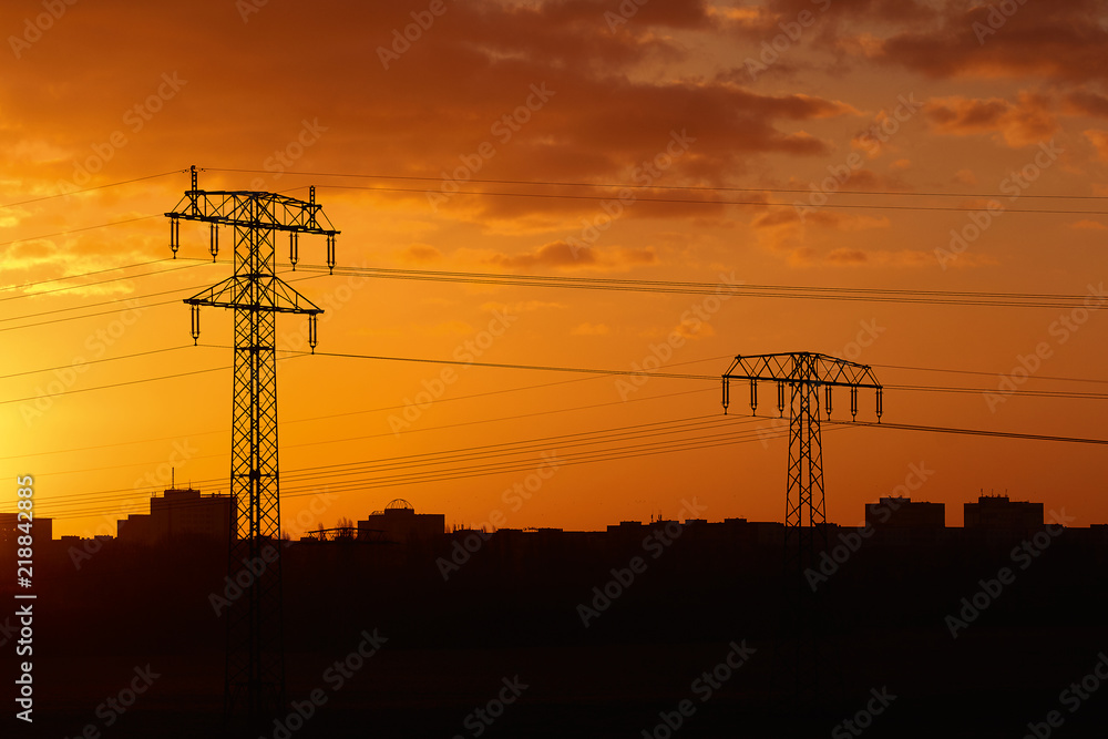 Stromtrasse vor einer Stadt im Sonnenaufgang