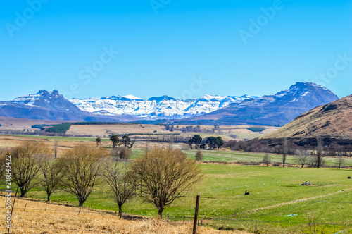 A blue and bright landscape with a lake and snow clad drakensberg mountains in a small country side village called under berg or underberg in Drakensberg area of Kwazulu Natal province in South Africa photo