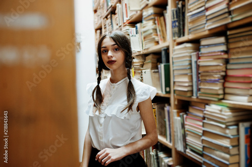 Girl with pigtails in white blouse at old library.