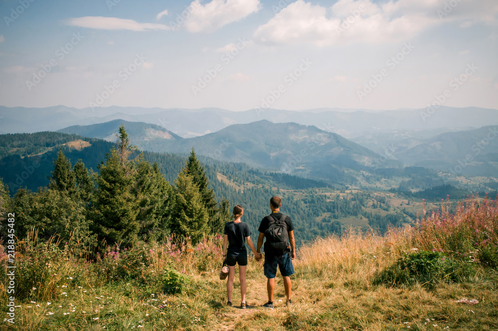 A guy and a girl hug each other on top of a mountain. Tourists enjoy the view of the Carpathian Mountains, Ukraine. Instagram filter.