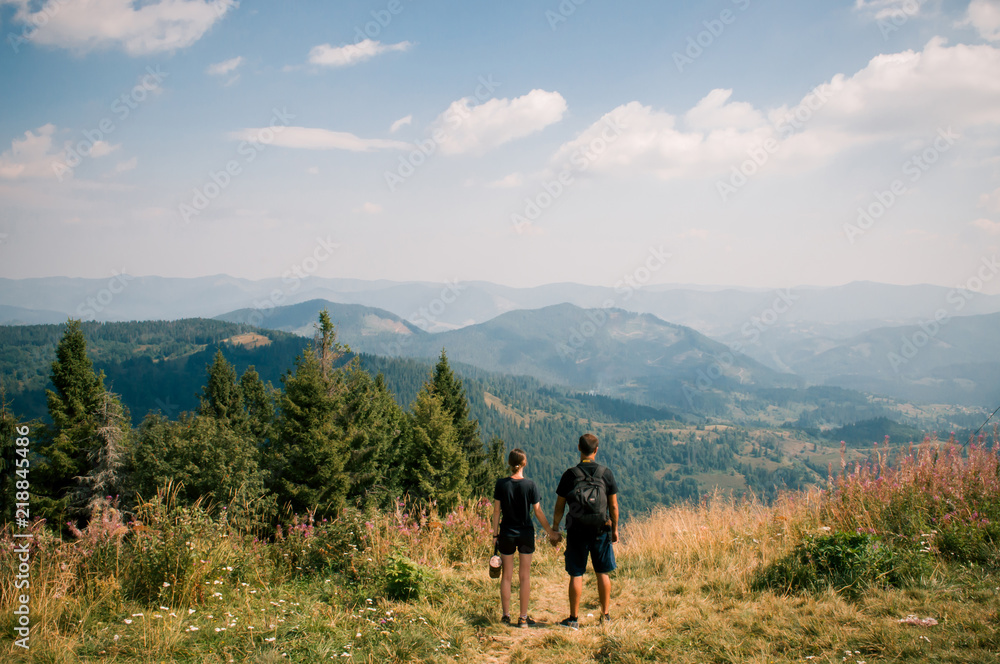 A guy and a girl hug each other on top of a mountain. Tourists enjoy the view of the Carpathian Mountains, Ukraine. Instagram filter.