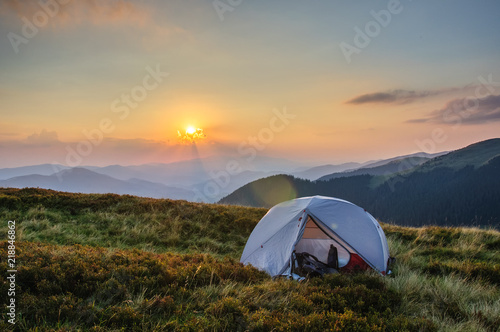 a gray tent on a grassy slope against the backdrop of a mountain range sunset in the Carpathians Ukraine