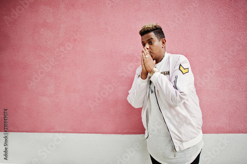 Stylish hipster arab man guy posed outdoor in street. Style rap singer against pink wall.